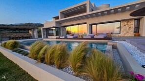 A modern house with a swimming pool, outdoor seating, and a stone facade. - Villa 7 Seas - With Amazing View (Lefkogia)