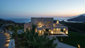 A modern two-story house with a stone facade, large windows, and a well-lit exterior. - Villa 7 Seas - With Amazing View (Lefkogia)