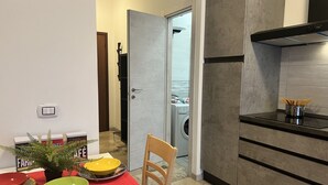A modern kitchen with a red table, a wooden chair, and a washing machine in the background. - Bnbook Studio Beatrice Rho Fiera (Rho)