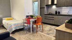 A compact hotel room with a bed, a small dining table, and a kitchenette. - Bnbook Studio Beatrice Rho Fiera (Rho)