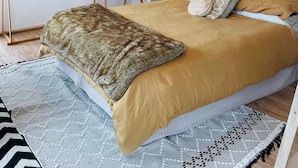 A bedroom with a bed, a bedside table, a hanging light fixture, and a wall-mounted artwork. - Country Studio Out West (Helensville)
