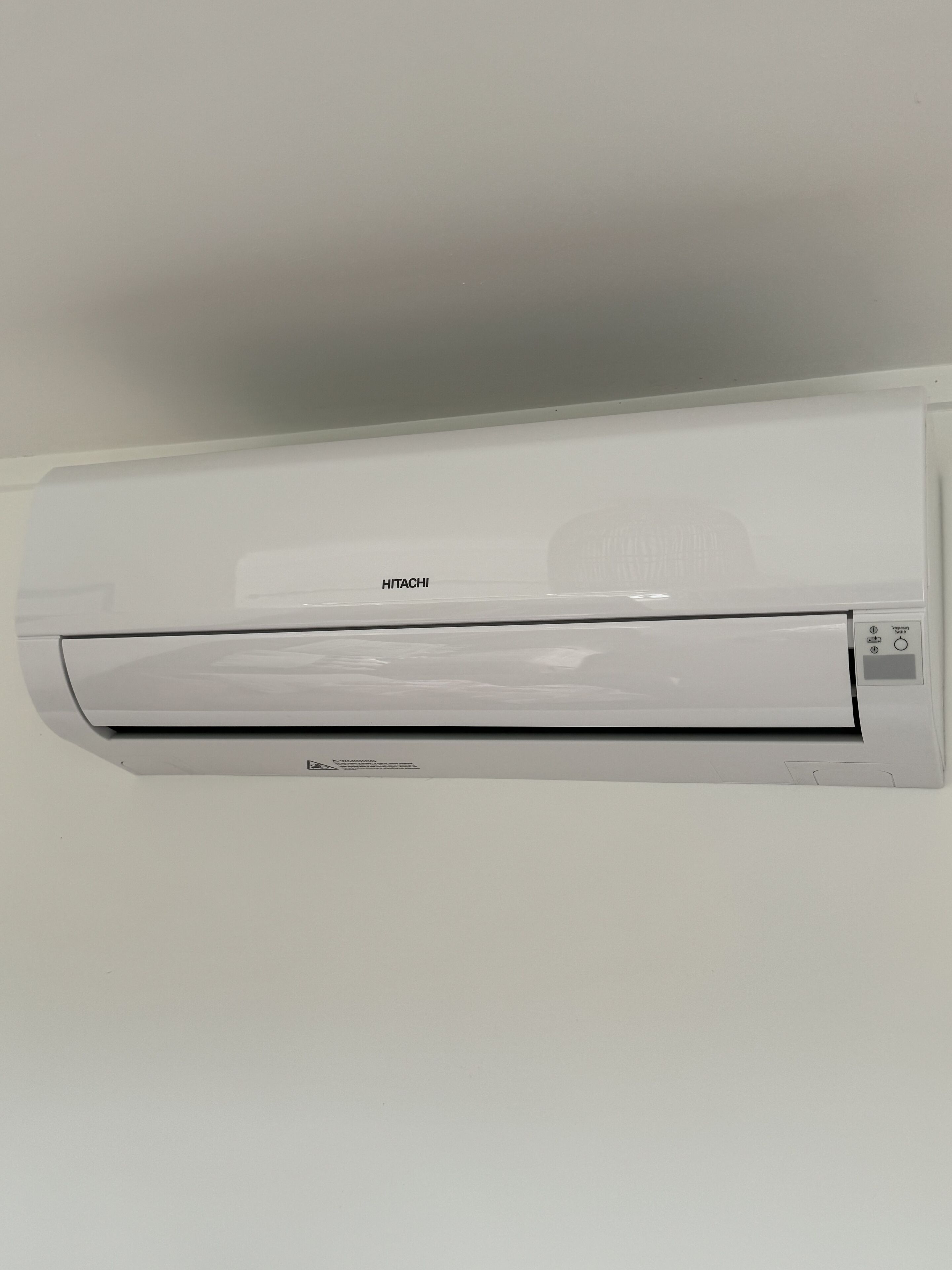 A white wall-mounted air conditioning unit with the brand name "HITACHI" visible.