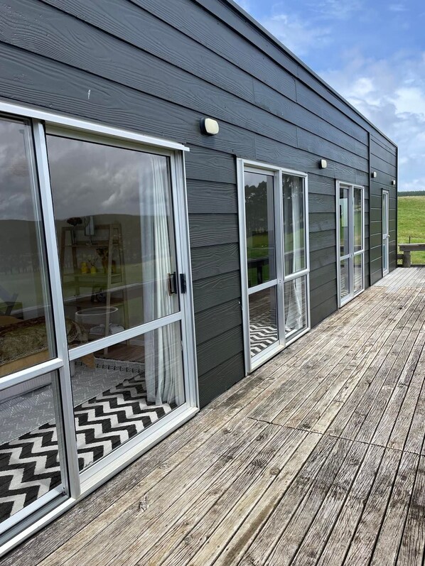 Un bâtiment moderne doté de grandes portes coulissantes en verre et d’une terrasse en bois.
