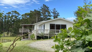 A single-story house with a covered porch, a fenced yard, and a clear blue sky.