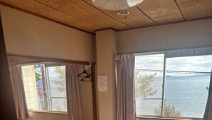 A room with a bed, two windows with curtains, a hanging rack, and a ceiling fan. - Pension Lakeside (Otsu)
