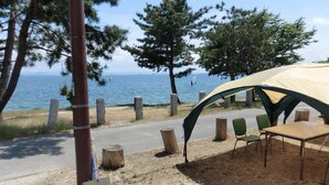 A camping area with a tent, chairs, and a table near a body of water. - Pension Lakeside (Otsu)