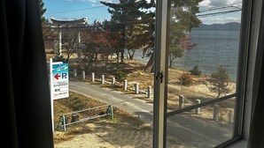 A view from a window with a clear sky, a sign with Japanese characters, and a body of water in the background. - Pension Lakeside (Otsu)
