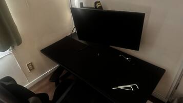 A black desk with a flat-screen TV, a keyboard, and a mouse.