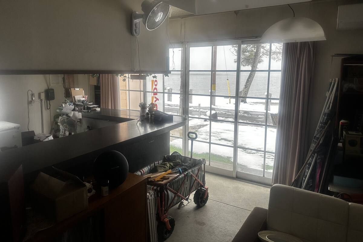 A kitchen with a large window, a fan, and a view of the sea.