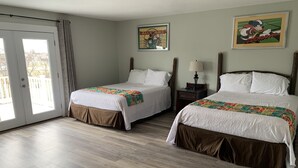 Ein Hotelzimmer mit zwei Betten, einer Schiebetür zu einem Balkon und einem gerahmten Bild an der Wand.