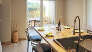 A modern kitchen with a large island, a sink, and a dining area with chairs and a table.