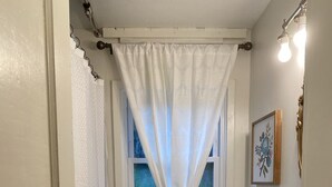 A bathroom with a toilet, sink, and window with a curtain.