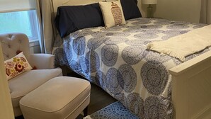 A bedroom with a bed, a chair, a lamp, and a hanging light fixture.