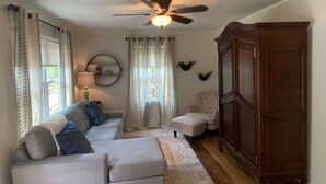A living room with a grey sectional sofa, a wooden cabinet, and a ceiling fan.