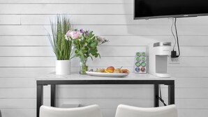 A modern kitchen with a white countertop, a coffee maker, a plate of fruit, and a vase of flowers. - Romantic Island Getaway for 2 on Navarre Beach. (Navarre)