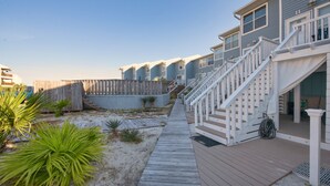 A wooden deck leading to a building with multiple balconies and a staircase. - Romantic Island Getaway for 2 on Navarre Beach. (Navarre)