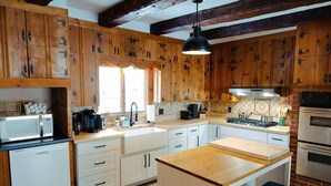 A kitchen with wooden cabinets, a microwave, a coffee maker, and a sink. - Authentic farmhouse for those who love cozy, quirky, historical imperfection (Randolph Center)