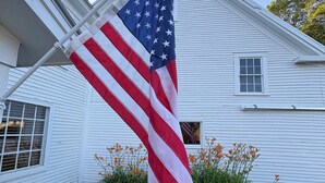 A white house with a flagpole holding an American flag. - Authentic farmhouse for those who love cozy, quirky, historical imperfection (Randolph Center)