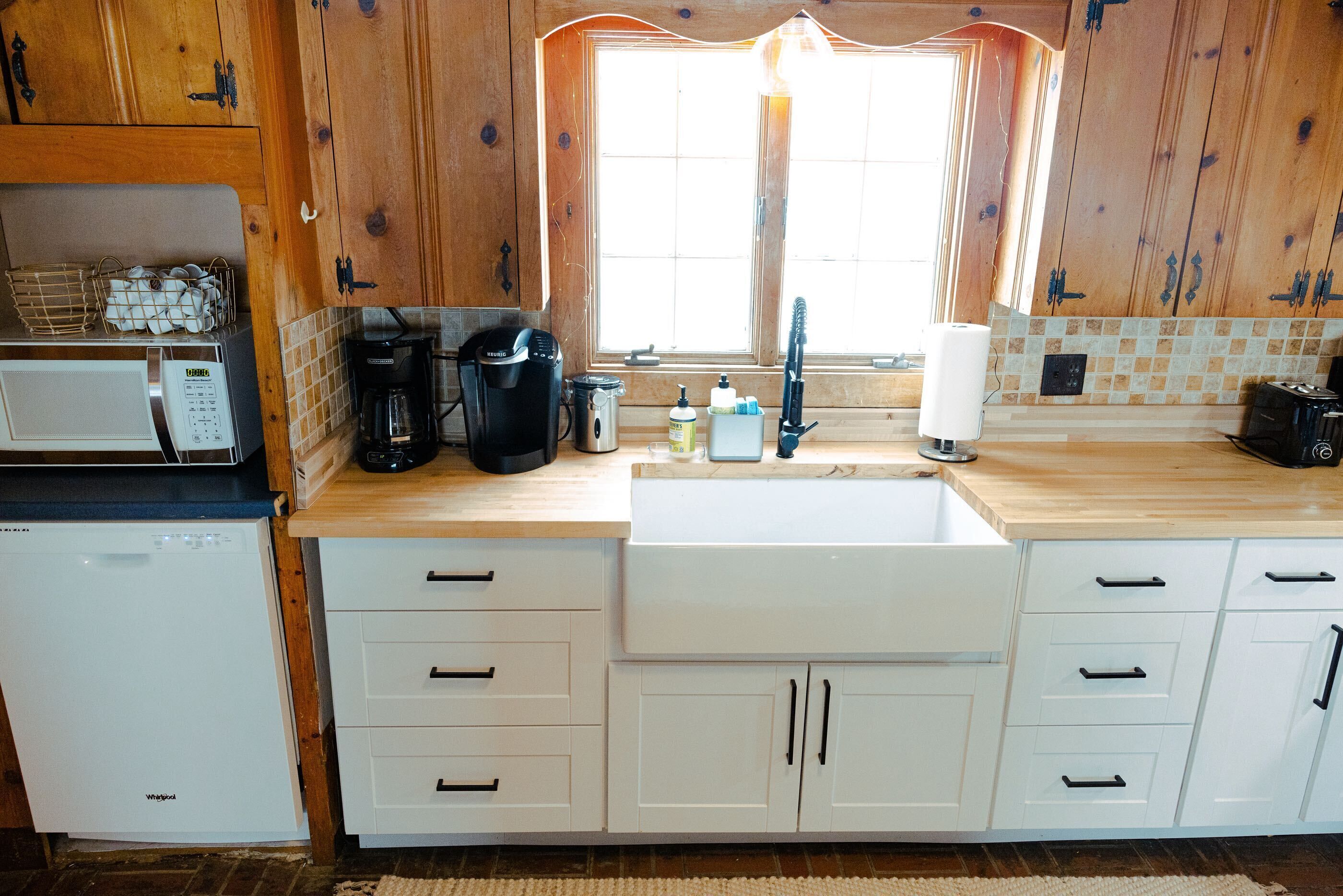 A kitchen with wooden cabinets, a sink, a microwave, a coffee maker, and a refrigerator.