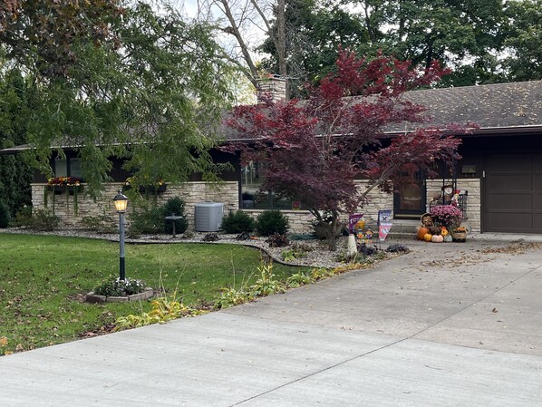 Una casa residencial con fachada de piedra, césped cuidado y entrada para vehículos.