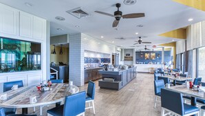 A modern restaurant with a central island, blue chairs, and a mix of white and wooden flooring. - Luxury Beachfront Studio, Endless Ocean Views, Resort Amenities, Newly Remodeled (Myrtle Beach)