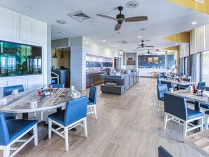Un restaurant moderne doté d’un îlot central, de chaises bleues et d’un mélange de revêtements de sol blancs et en bois.