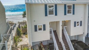 Ein zweistöckiges Gebäude mit einem Balkon mit Blick auf einen Strand.