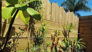 Une terrasse en bois agrémentée de plantes en pot et d’une clôture en bois.