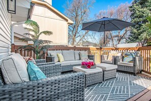 Een patio met rieten meubilair, een grote parasol en een decoratieve muur.