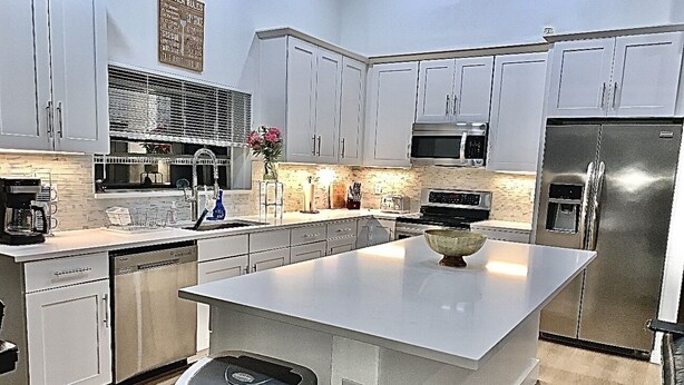 A modern kitchen with white cabinets, stainless steel appliances, and a central island. - Luxury 4/bed w/Pool & Putt Grn (Peoria)