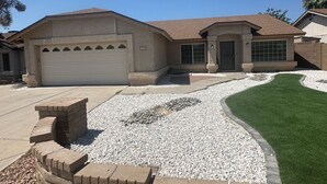 A residential house with a garage, a driveway, and a well-maintained lawn. - Luxury 4/bed w/Pool & Putt Grn (Peoria)
