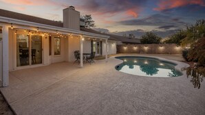 A backyard with a swimming pool, a covered patio, and string lights. - Luxury 4/bed w/Pool & Putt Grn (Peoria)