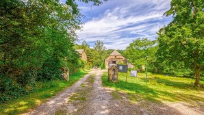 A rural road leading to a stone building with a thatched roof, surrounded by lush greenery and trees. - Luxurious apartment in Saint-Affrique (Saint-Affrique)
