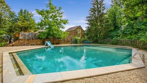 A rectangular swimming pool with a stone wall and a wooden fence surrounding it. - Luxurious apartment in Saint-Affrique (Saint-Affrique)
