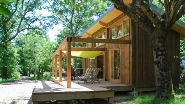 A wooden cabin with a covered porch, outdoor seating, and a view of the surrounding forest. - Luxurious apartment in Saint-Affrique (Saint-Affrique)