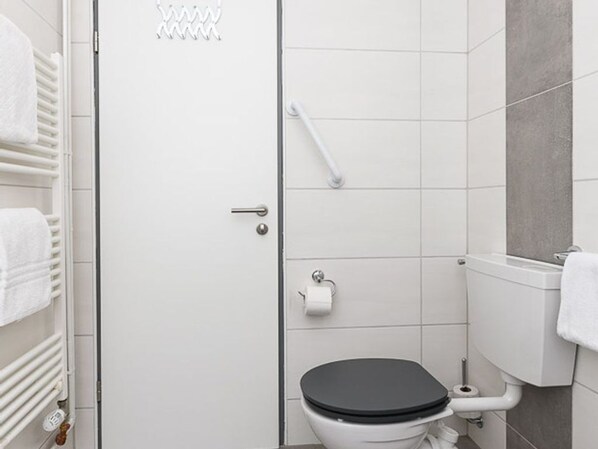 A bathroom with a toilet, a towel rack, and a shower area.