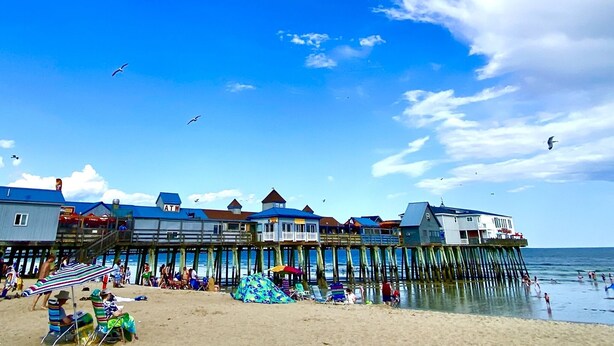 A pier with beachside accommodations, including a visible ATM, and a sandy beach with people and umbrellas. - Spacious & sunny, 7 minutes from the beach! (Old Orchard Beach)