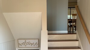A staircase with white railings and wooden steps leading to a landing. A 'welcome' sign is visible above the staircase. - Spacious & sunny, 7 minutes from the beach! (Old Orchard Beach)