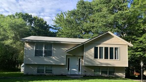 A two-story house with a front door, two windows on the ground floor, and a small porch. - Spacious & sunny, 7 minutes from the beach! (Old Orchard Beach)