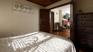 Un dormitorio con cama, cómoda de madera, escritorio con silla y televisor.