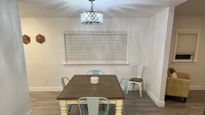 Un comedor con mesa de madera, sillas azul claro y una araña.