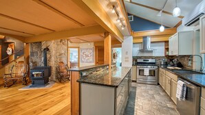 Una cocina amplia con pared de piedra, piso de madera y electrodomésticos modernos.