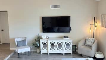 A living room with a ceiling fan, a flat-screen TV, a white entertainment unit, two sofas, and a coffee table.