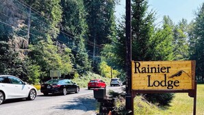 A wooden sign for Rainier Lodge with a mountain and a bird illustration.