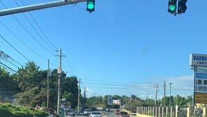 A multi-lane road with traffic lights, vehicles, and a billboard. - Magic casa (Kingston)