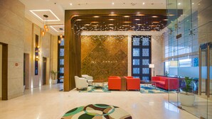 A modern lobby with a geometric light fixture, a patterned rug, and a red seating area. - Best Western Plus Chandigarh Mohali. (Mohali)