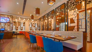 A modern restaurant with a long dining table, colorful chairs, and a TV screen. - Best Western Plus Chandigarh Mohali. (Mohali)