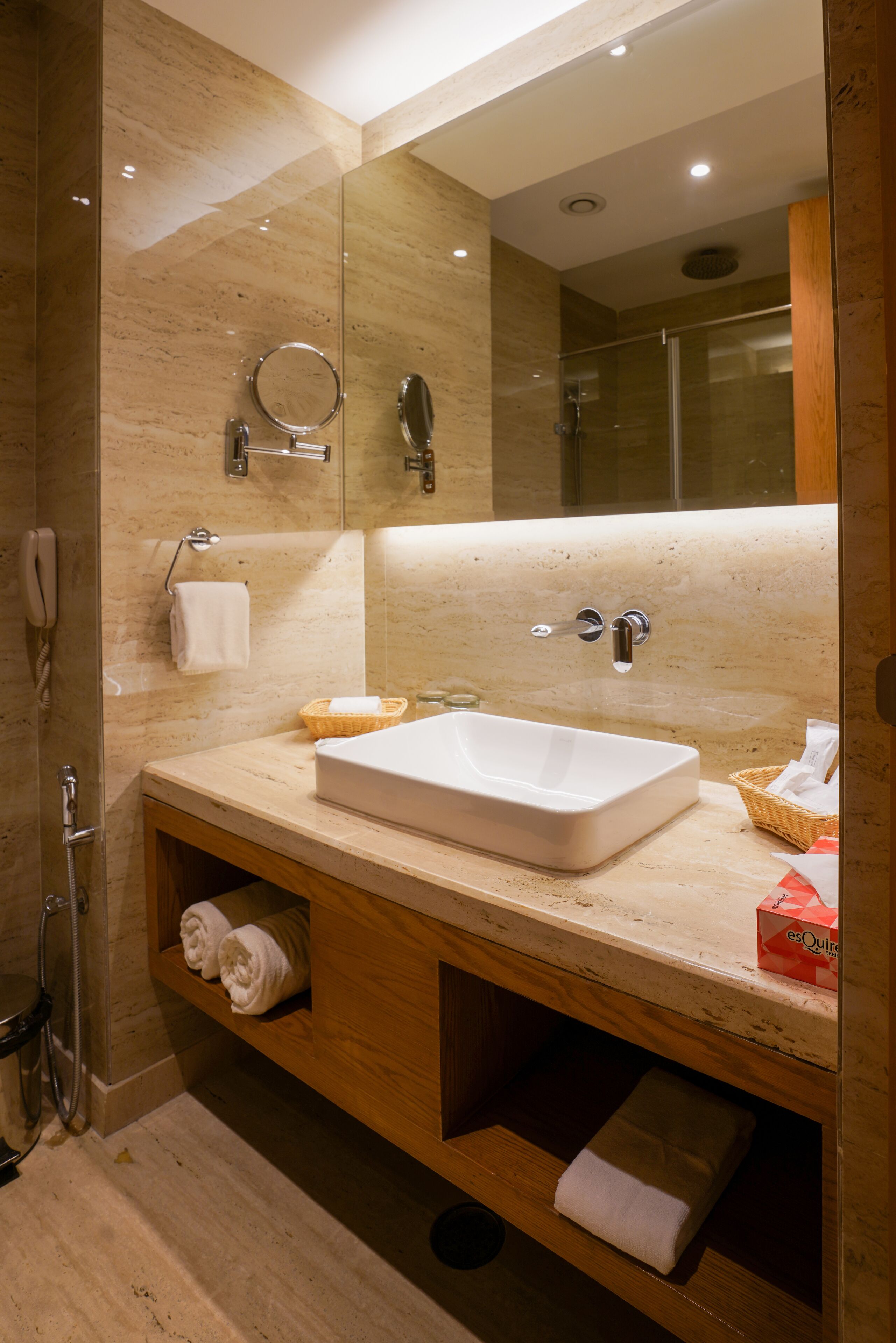 A modern bathroom with a large mirror, a sink, and a shower.
