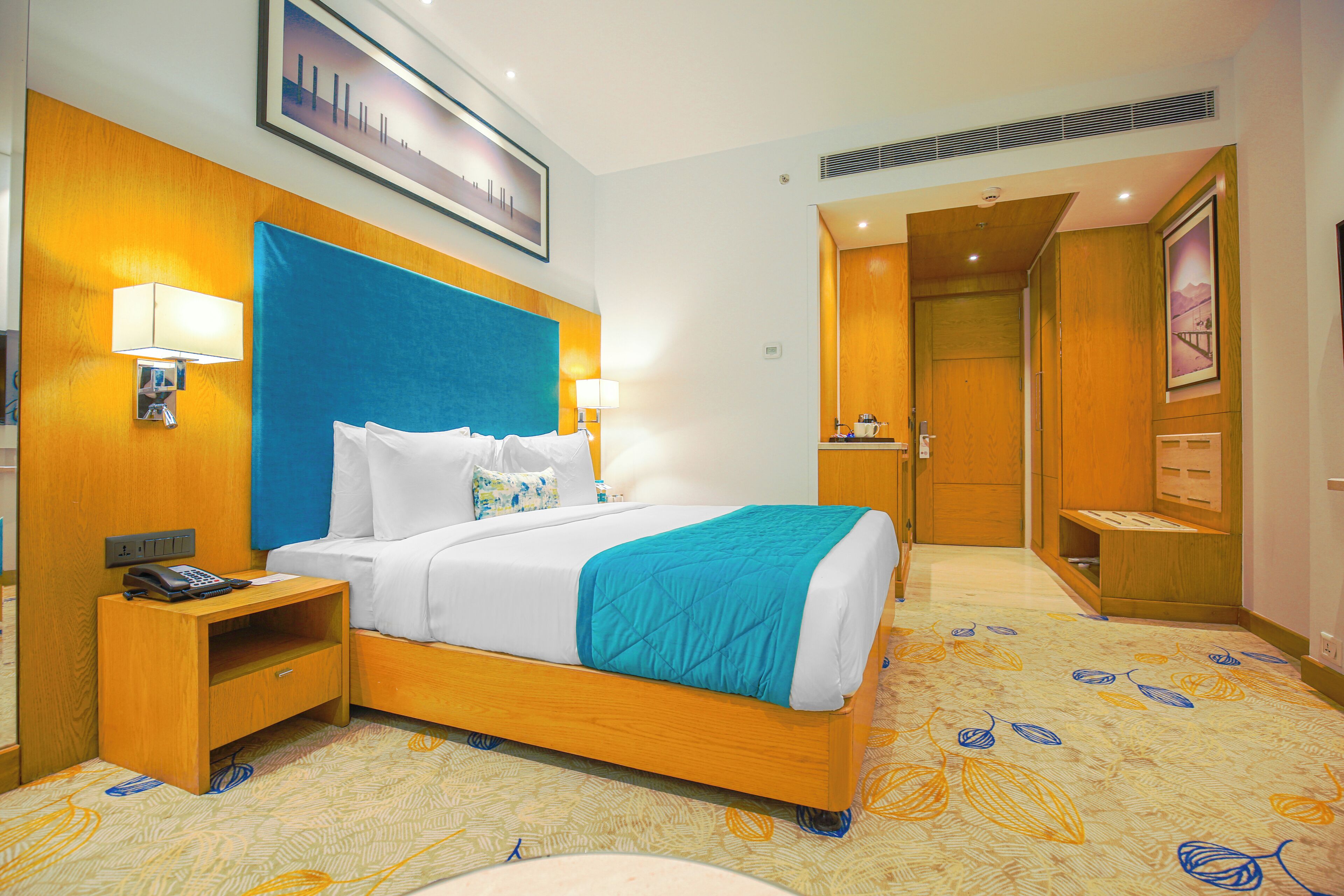 A hotel room with a bed, bedside lamps, a nightstand, and a wooden headboard.