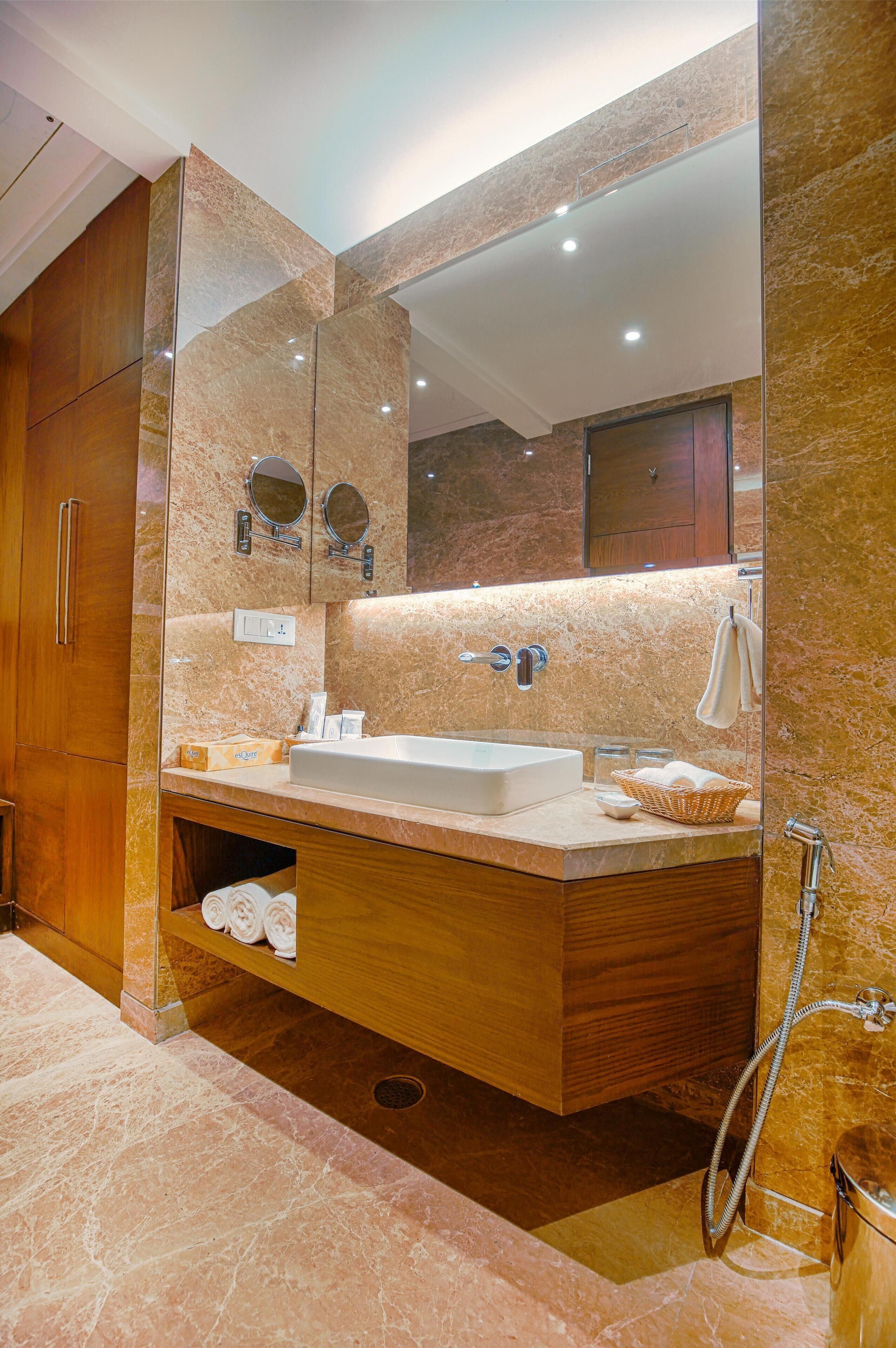 A modern bathroom with a large mirror, wooden vanity, and a shower area.